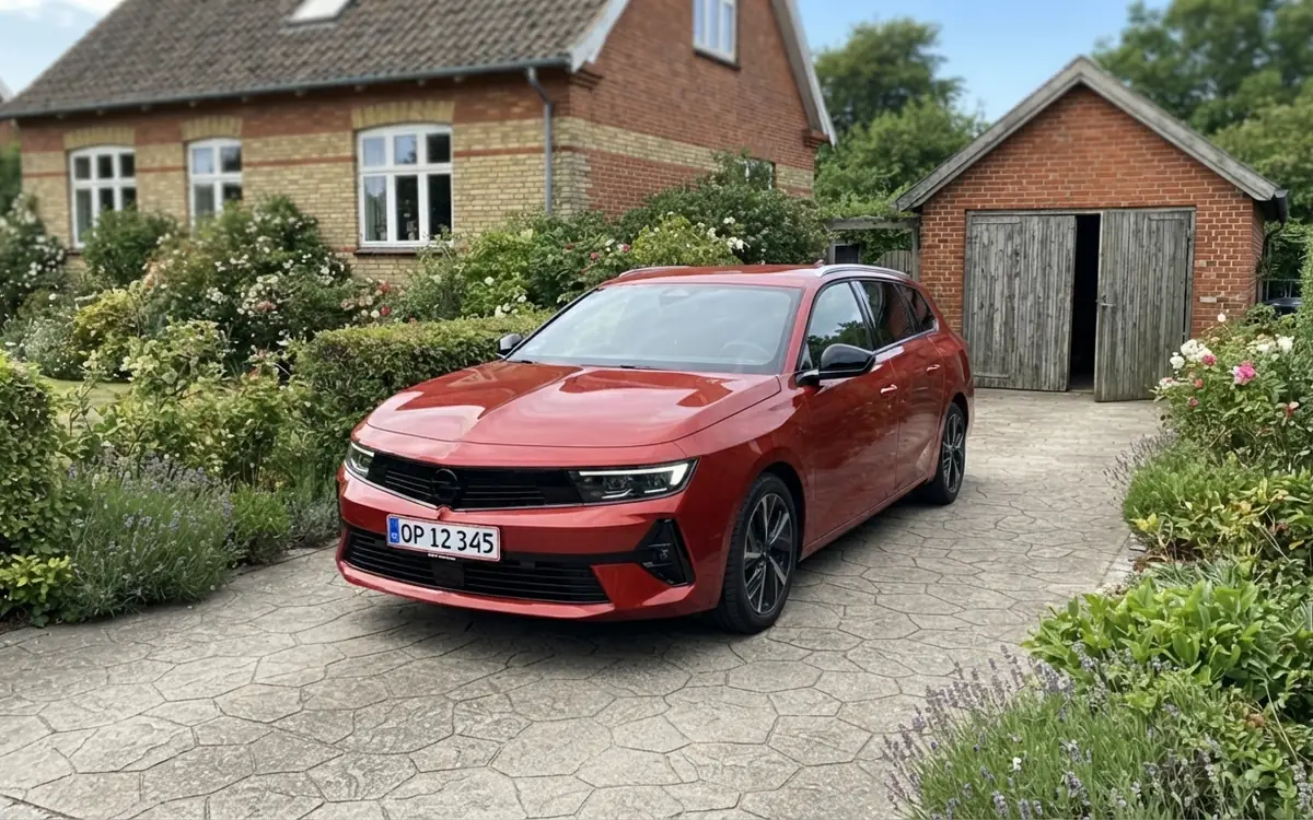 Röd Opel Astra Sports Tourer parkerad på en uppfart vid ett äldre hus